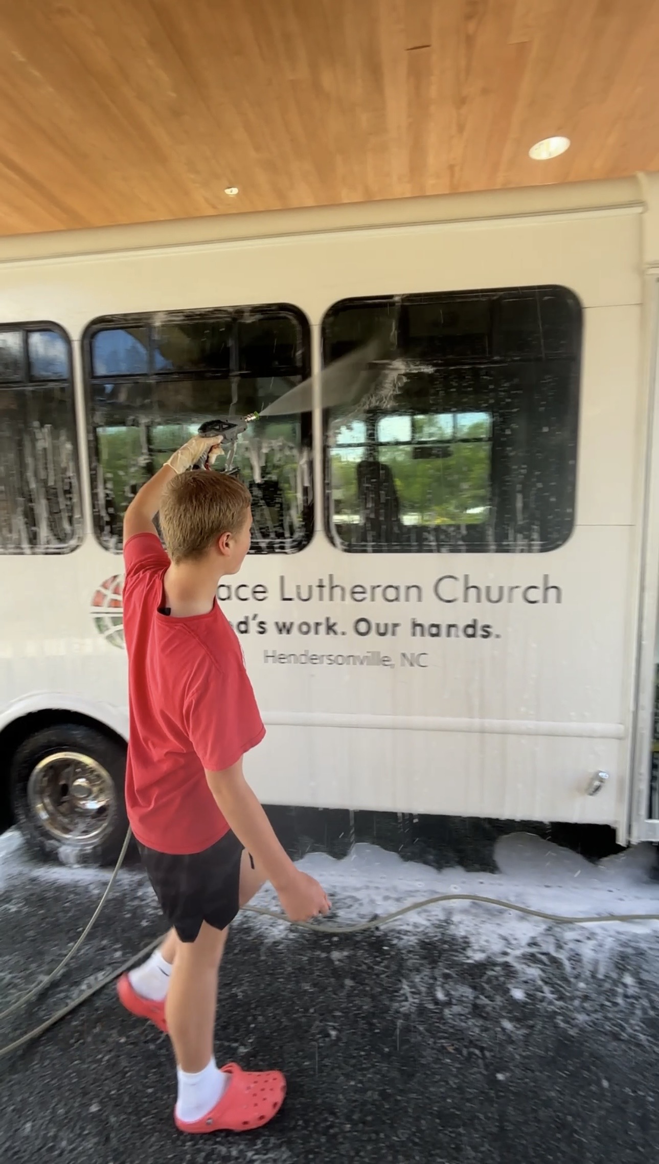 Rinsing the soapy windows of a shuttle bus clean