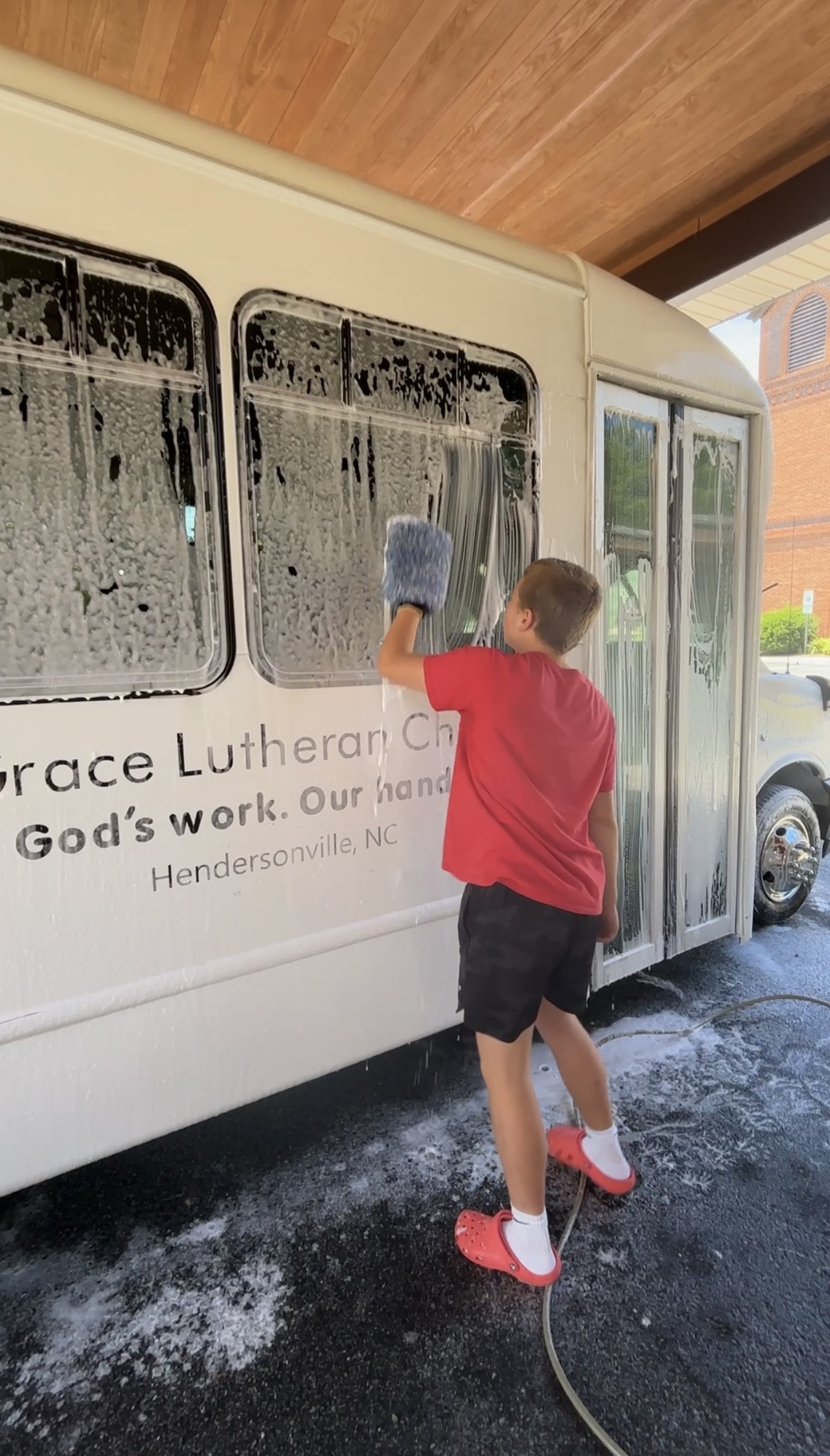 Hand washing soapy bus windows with a wash mitt