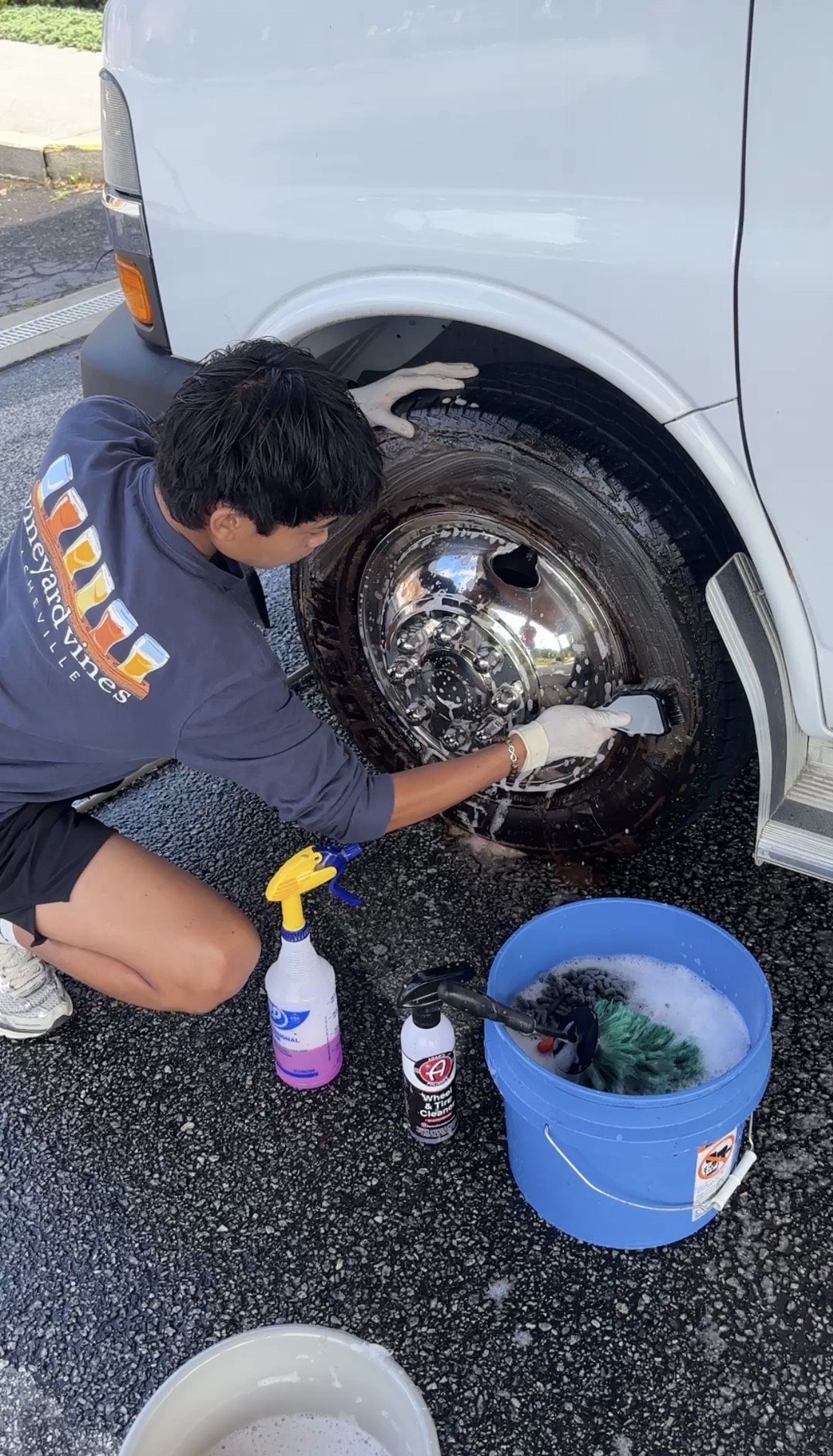 Scrubbing a chrome van wheel with a brush and bucket of suds
